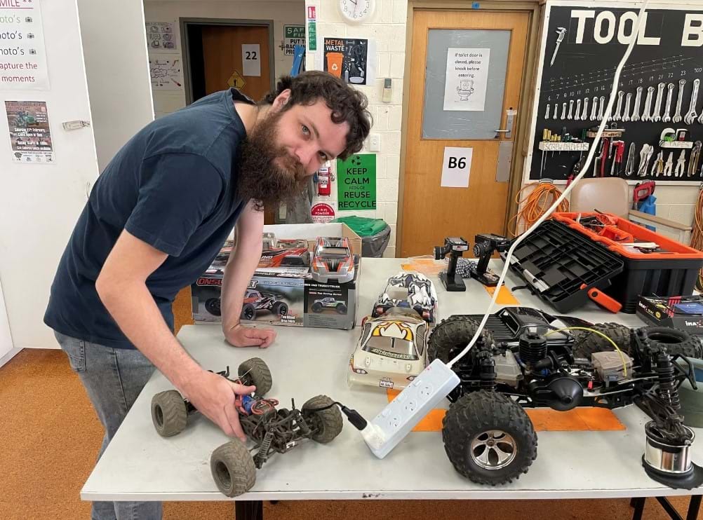 a man showing remote control car and other remote control cars on table Disability supports Bairnsdale