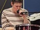 Lady singing into microphone while playing drums at Distinctive Options Noweyung