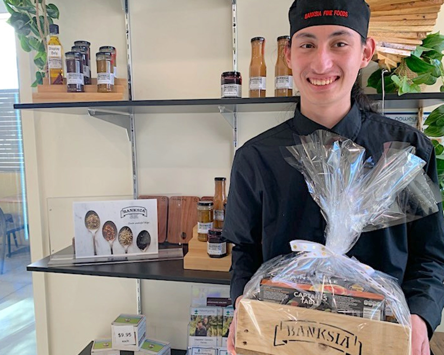 A young man holds a gift hamper at NDIS registered disability support Distinctive Options
