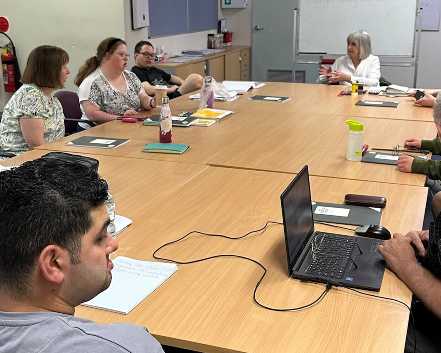 A group of people at a table in a discussion at NDIS registered disability service Distinctive Options