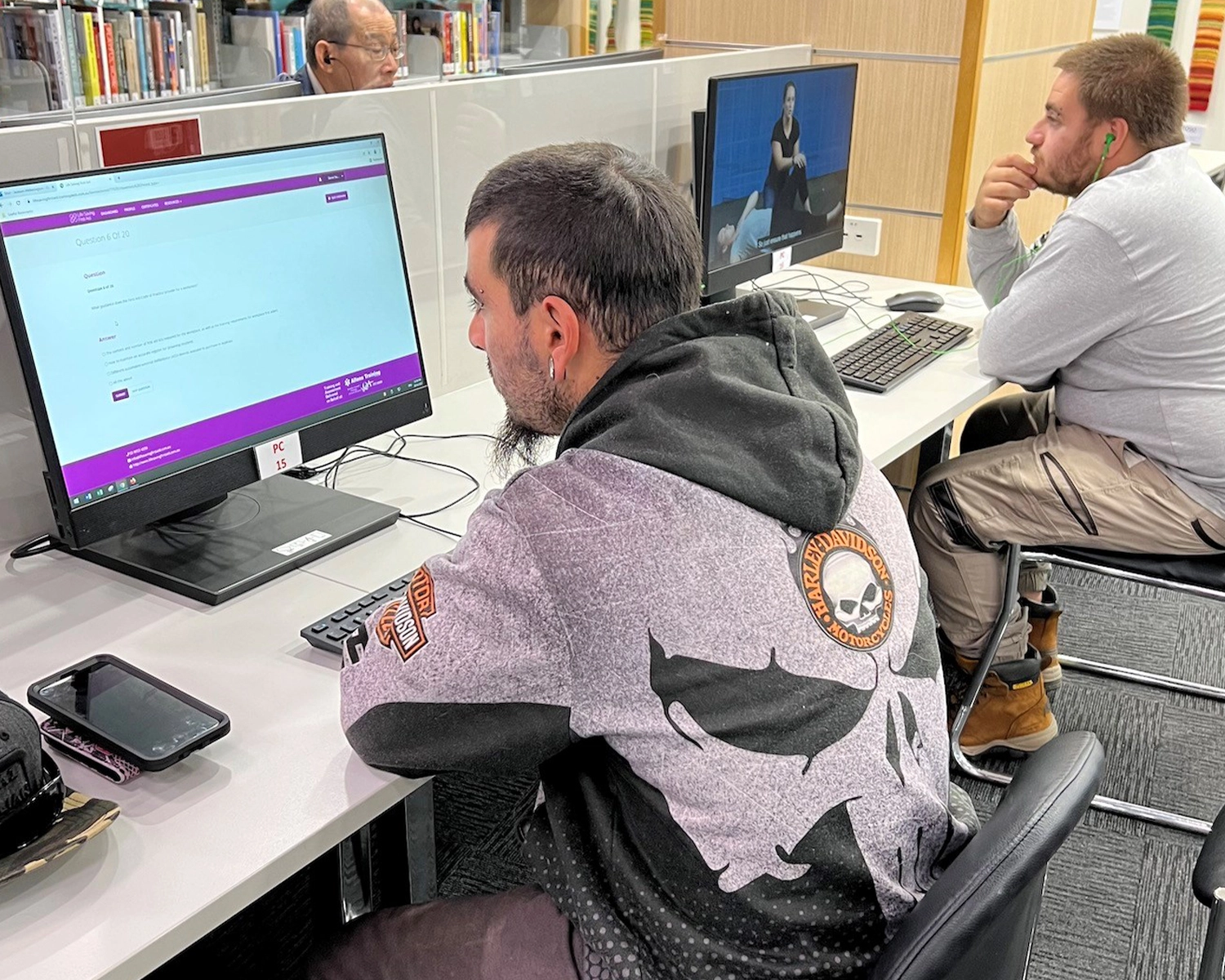 Two men work at computer screens in a library for literacy skills Distinctive Options