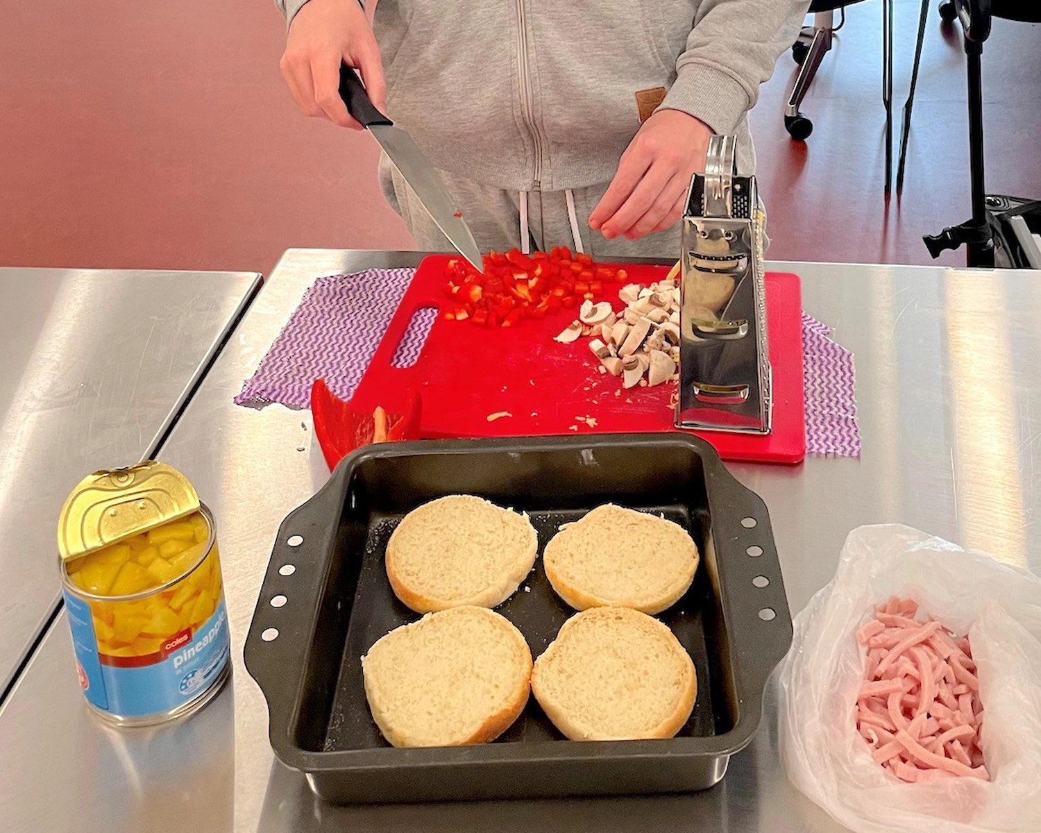 a man uses a knife to spread butter on burger buns at Distinctive Options Brimbank lunch making activity