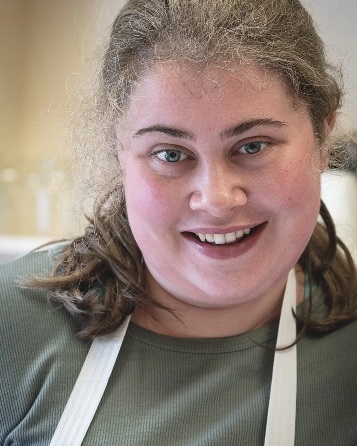 A woman wears an apron and smiles at NDIS registered disability service Distinctive Options