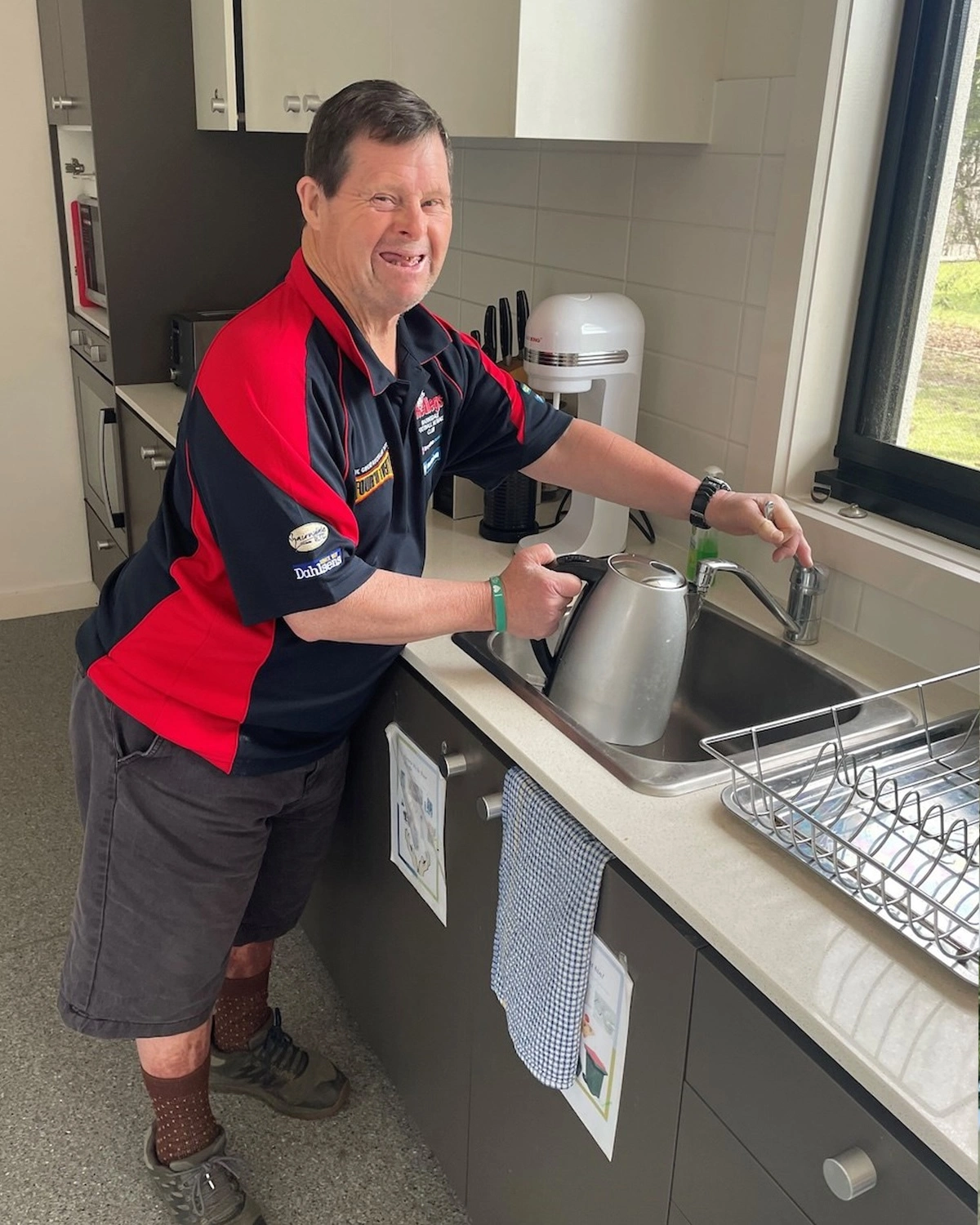A man fills a kettle with water at NDIS registered disability service Distinctive Options independent living supports