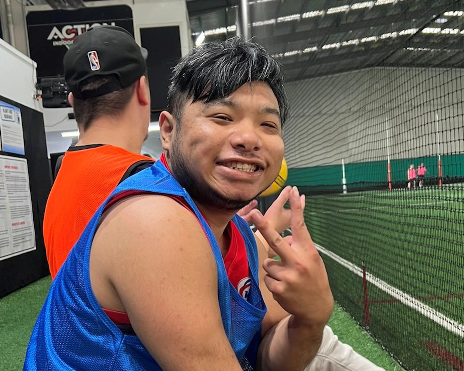 A man smiles while at a sports stadium at NDIS registered disability service Distinctive Options