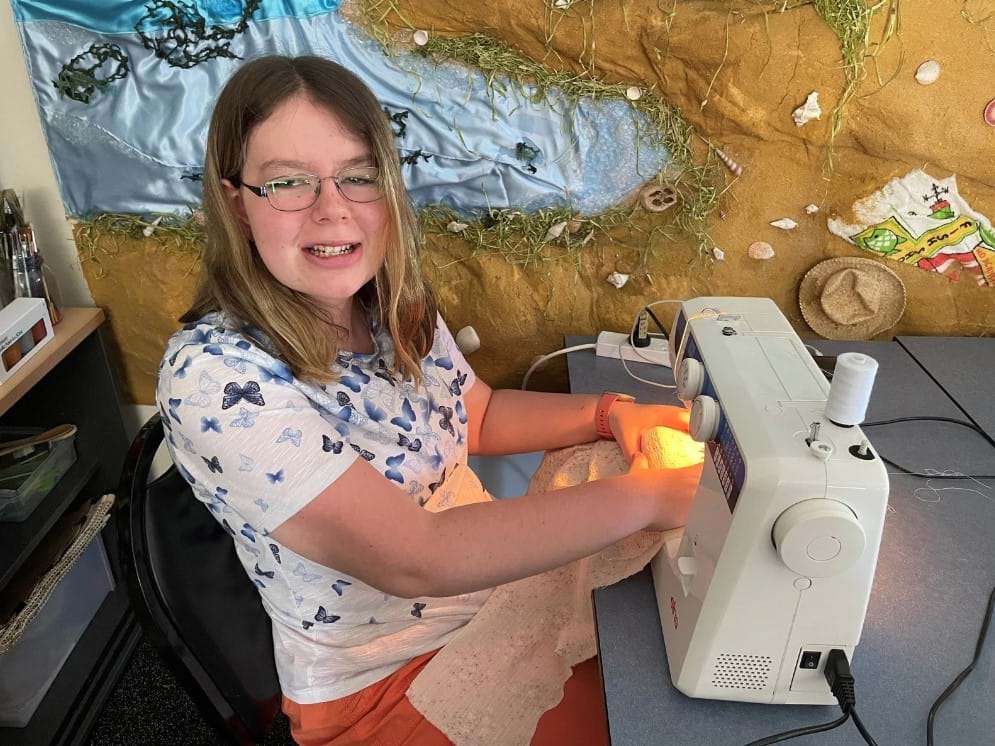 Jess operates a sewing machine at Group Supports Creative Arts at Distinctive Options Noweyung