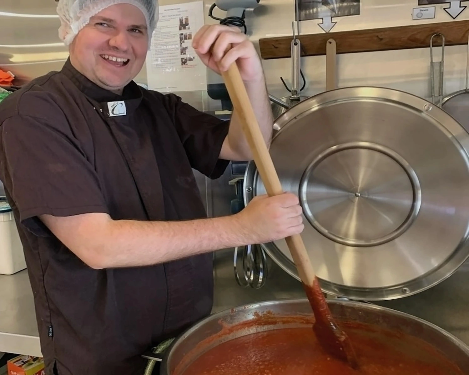 A man stirs a pot in a kitchen Distinctive Options Supported employment social enterprise