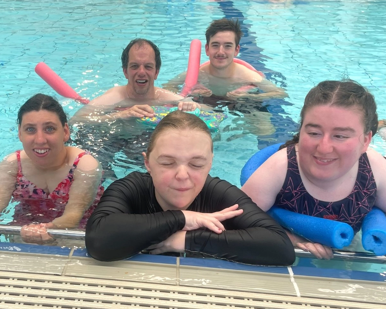 A group of people in a swimming pool with supports