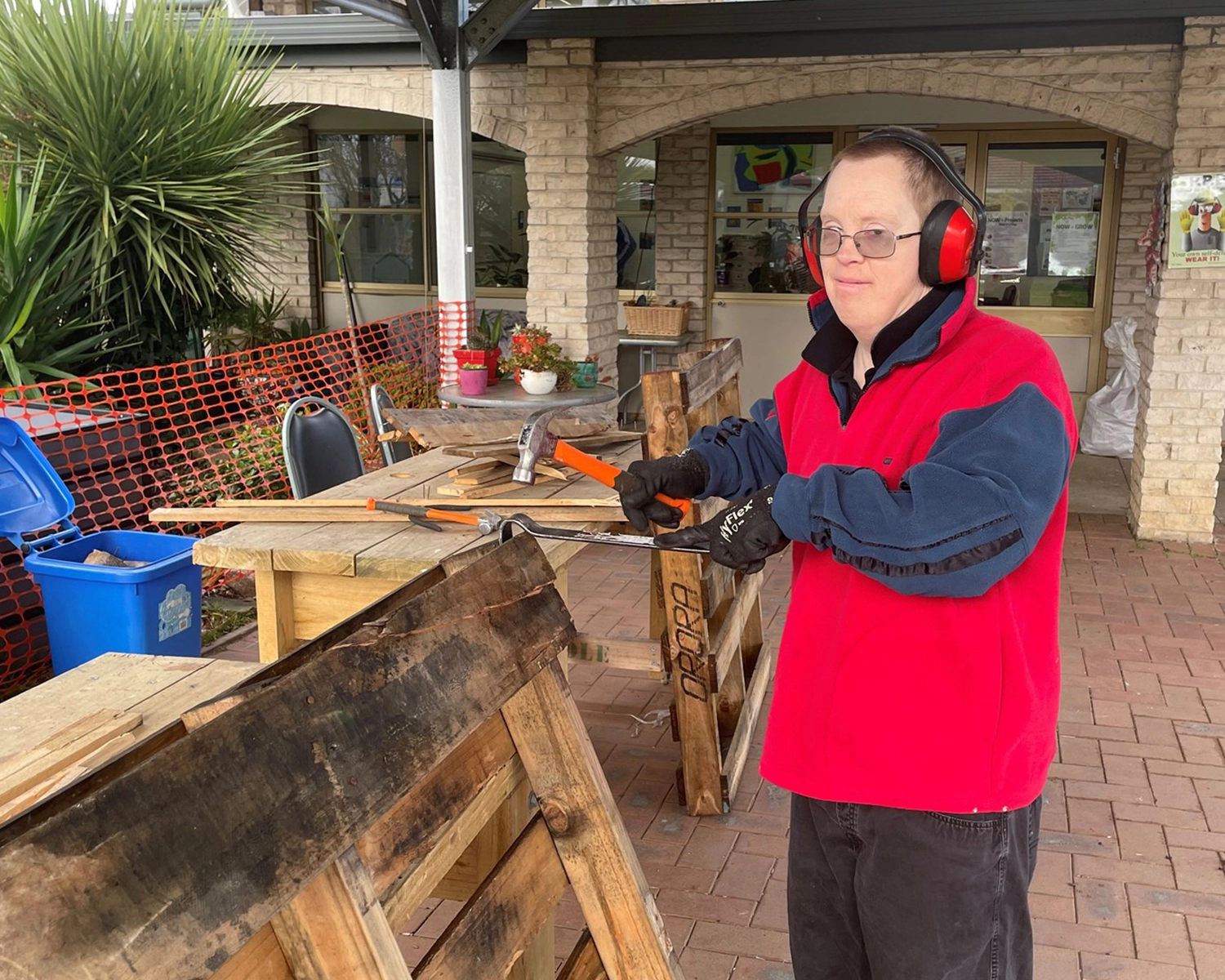 a man wears safety clothing while handling timber at Group Supports Woodwork and My Projects at Distinctive Options Noweyung