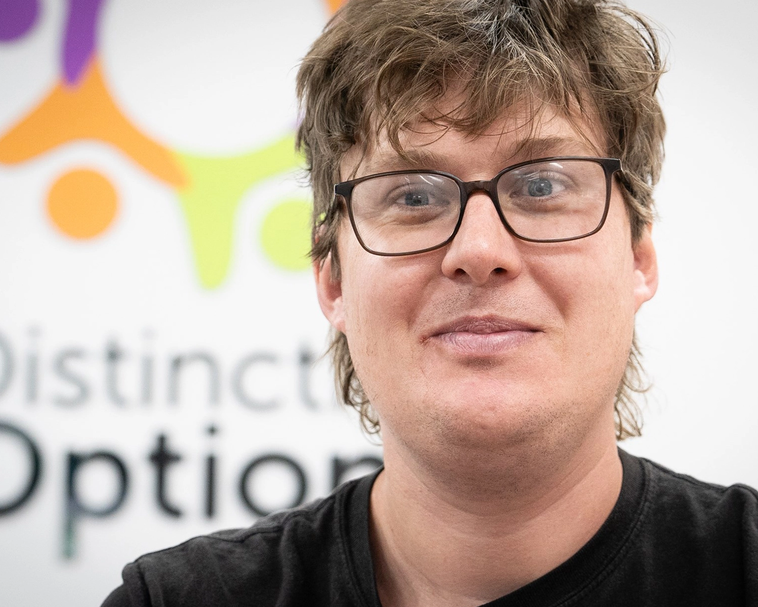 a man wearing glass smiles and looks at camera